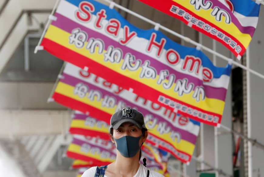 En kvinde, der bærer en beskyttelsesmaske, går ned under bannerne, der læser "Stay Home" i Tokyo, hvor undtagelsestilstanden vil forblive på plads på trods af at hun blev løftet i 39 andre præfekturer torsdag. | REUTERS